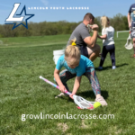 Micro lacrosse player practicing scooping the ball.