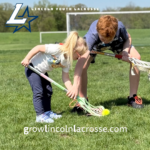 Micro lacrosse player learning from older athlete.